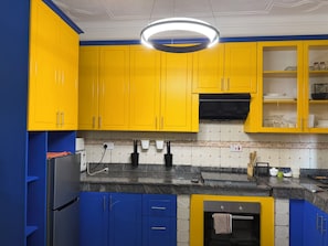 Eine Küche mit gelben Schränken, einem Edelstahl-Kühlschrank und einem eingebauten Backofen.