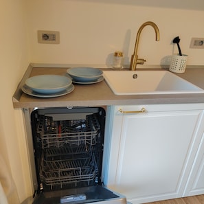 A kitchen with a white sink, a gold faucet, and two blue plates on the countertop. - "Il Mondo Nuovo," a modern and cozy apartment in Porta Nuova. (Milano)