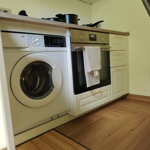 A compact kitchen with a built-in washer and dryer, a small oven, and a countertop with pots. - "Il Mondo Nuovo," a modern and cozy apartment in Porta Nuova. (Milano)