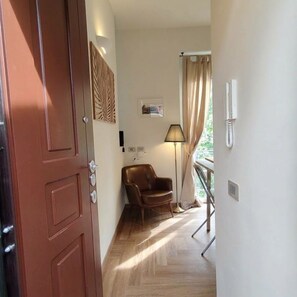 A hotel room with a wooden floor, a brown leather chair, a standing lamp, and a window with curtains. - "Il Mondo Nuovo," a modern and cozy apartment in Porta Nuova. (Milano)