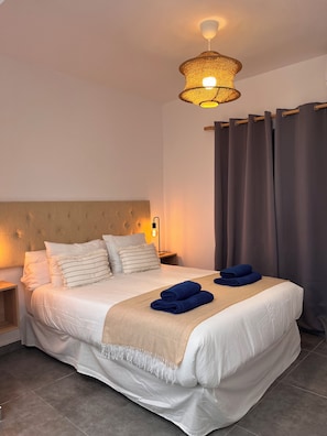 A neatly made bed with a headboard, a bedside lamp, and a folded towel on the bed. - Pescante 2 Apartment. Playa Honda (Playa Honda)