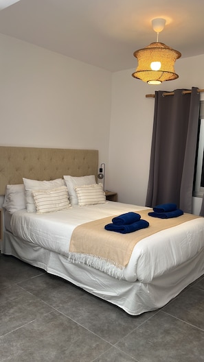 A neatly made bed with a headboard, a bedside lamp, and a window with curtains. - Pescante 2 Apartment. Playa Honda (Playa Honda)