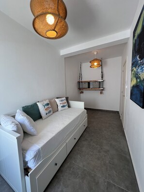 A compact room with a white sofa, a hanging light fixture, and a painting on the wall. - Pescante 2 Apartment. Playa Honda (Playa Honda)