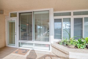 A house entrance with a door, large sliding glass doors, and a planter with plants. - Towers 4104 in Ponce Inlet, FL (Ponce Inlet)