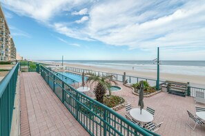 A balcony with a view of the beach, a pool, and outdoor seating. - Towers 4104 in Ponce Inlet, FL (Ponce Inlet)