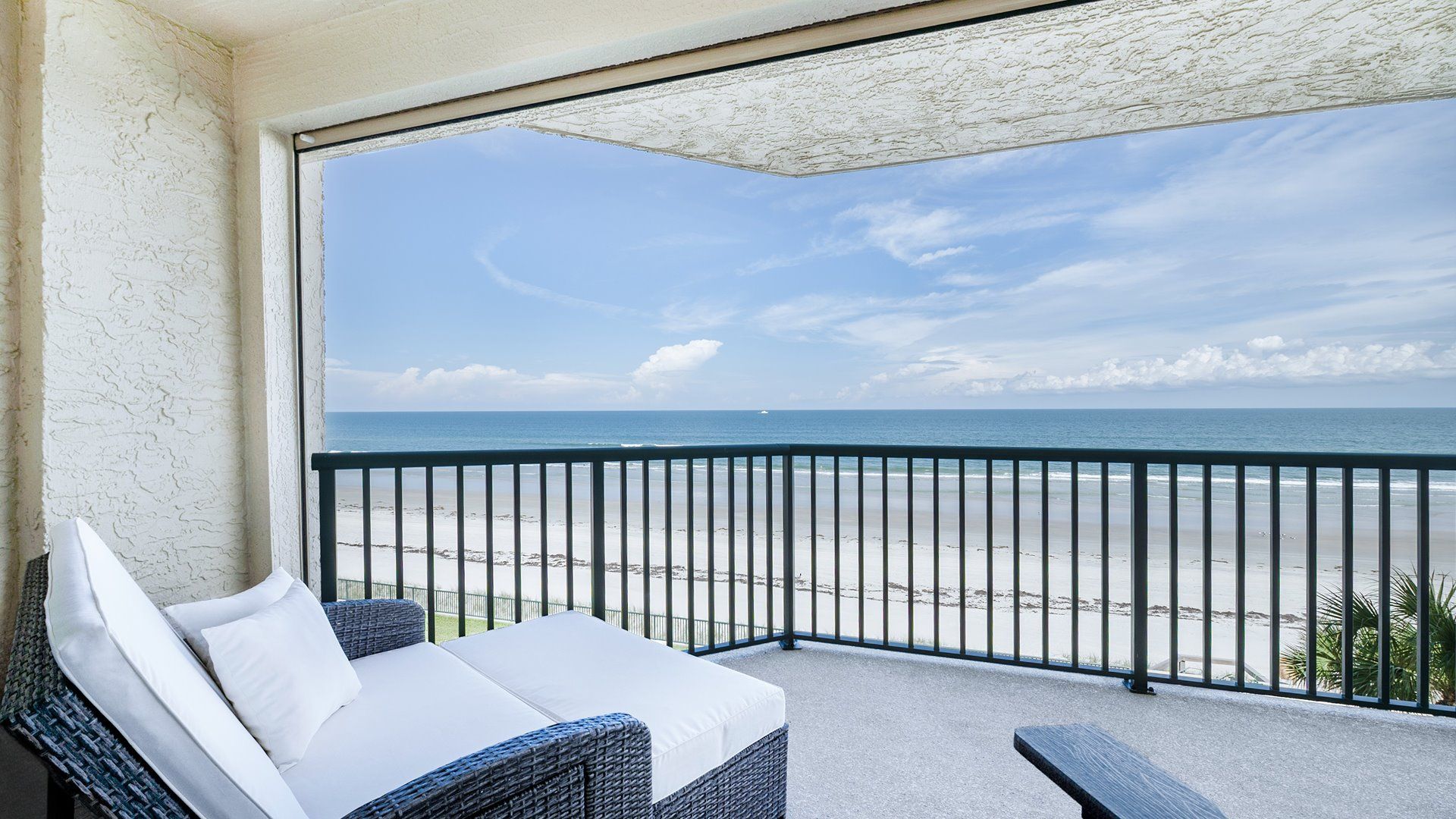 A balcony with a view of the beach and ocean.