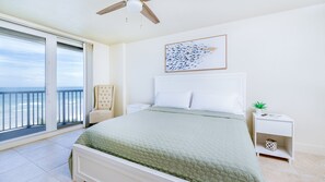 A bedroom with a bed, a nightstand, a chair, a ceiling fan, a window with a view of the ocean, and a framed picture on the wall. - #7306 Towers 8&9 Oceanfront 2/2 condo (Ponce Inlet)