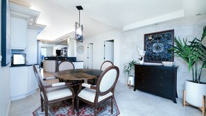 A dining area with a round table, chairs, a decorative ceiling light, a wall-mounted painting, and a potted plant. - #7306 Towers 8&9 Oceanfront 2/2 condo (Ponce Inlet)