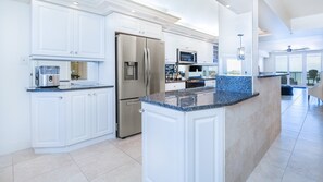 A modern kitchen with white cabinetry, stainless steel appliances, and a granite countertop. - #7306 Towers 8&9 Oceanfront 2/2 condo (Ponce Inlet)