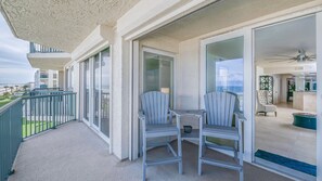 A balcony with two chairs and a table, a sliding glass door, and a view of the ocean. - #7306 Towers 8&9 Oceanfront 2/2 condo (Ponce Inlet)