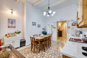 A dining area with a wooden table and chairs, a white cabinet, and a patterned floor. - 2BR Maltese Townhouse in Bormla close to harbour (Cospicua)