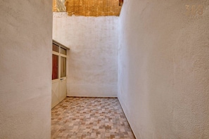 A narrow hallway with a tiled floor and a window with curtains. - 2BR Maltese Townhouse in Bormla close to harbour (Cospicua)