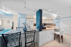 A modern kitchen with a central island, white cabinetry, and a blue accent wall. - Towers at Ponce Inlet 1206 (Ponce Inlet)