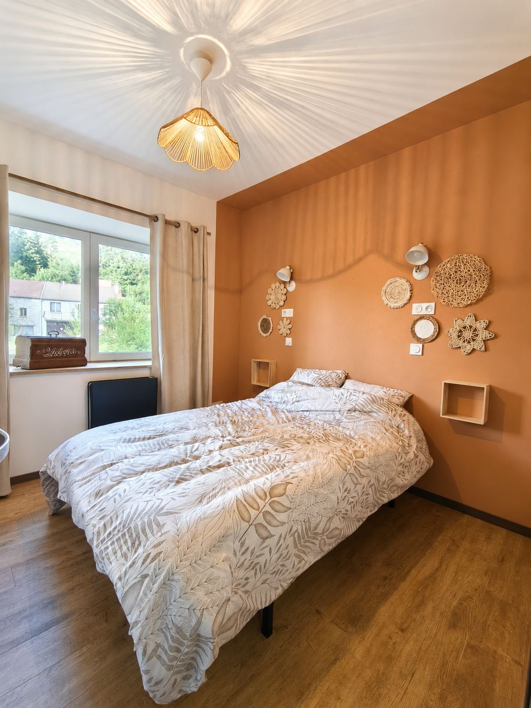 A bedroom with a large bed, a ceiling light fixture, and wall-mounted decor.