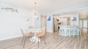 A modern kitchen with white cabinets, a stainless steel refrigerator, and a central island with bar stools. - #3502  Ponce Inlet Oceanfront (Ponce Inlet)