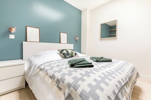 A bedroom with a bed, a nightstand, a wall-mounted shelf, and framed artwork. - Luxueux Logement Design 4 ch Clim (Lille)