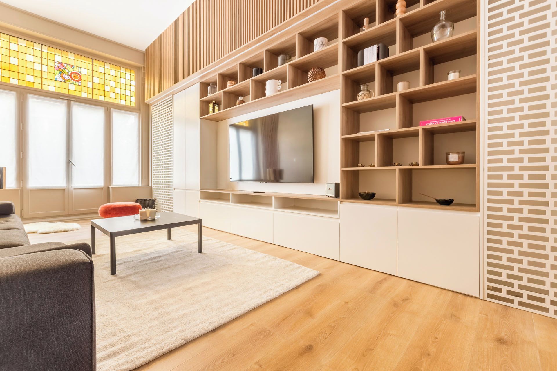 Ein modernes Wohnzimmer mit Flachbildfernseher, Holzregalen und einer Couch.
