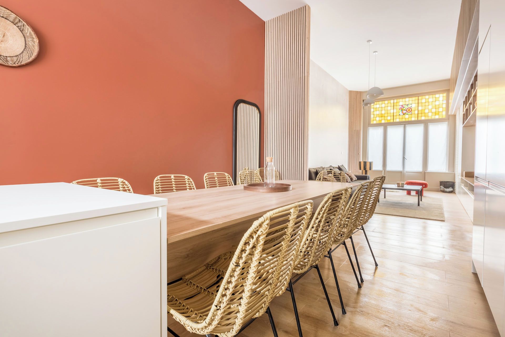 Ein Essbereich mit einem langen Tisch, Korbstühlen und modernem Interieur.