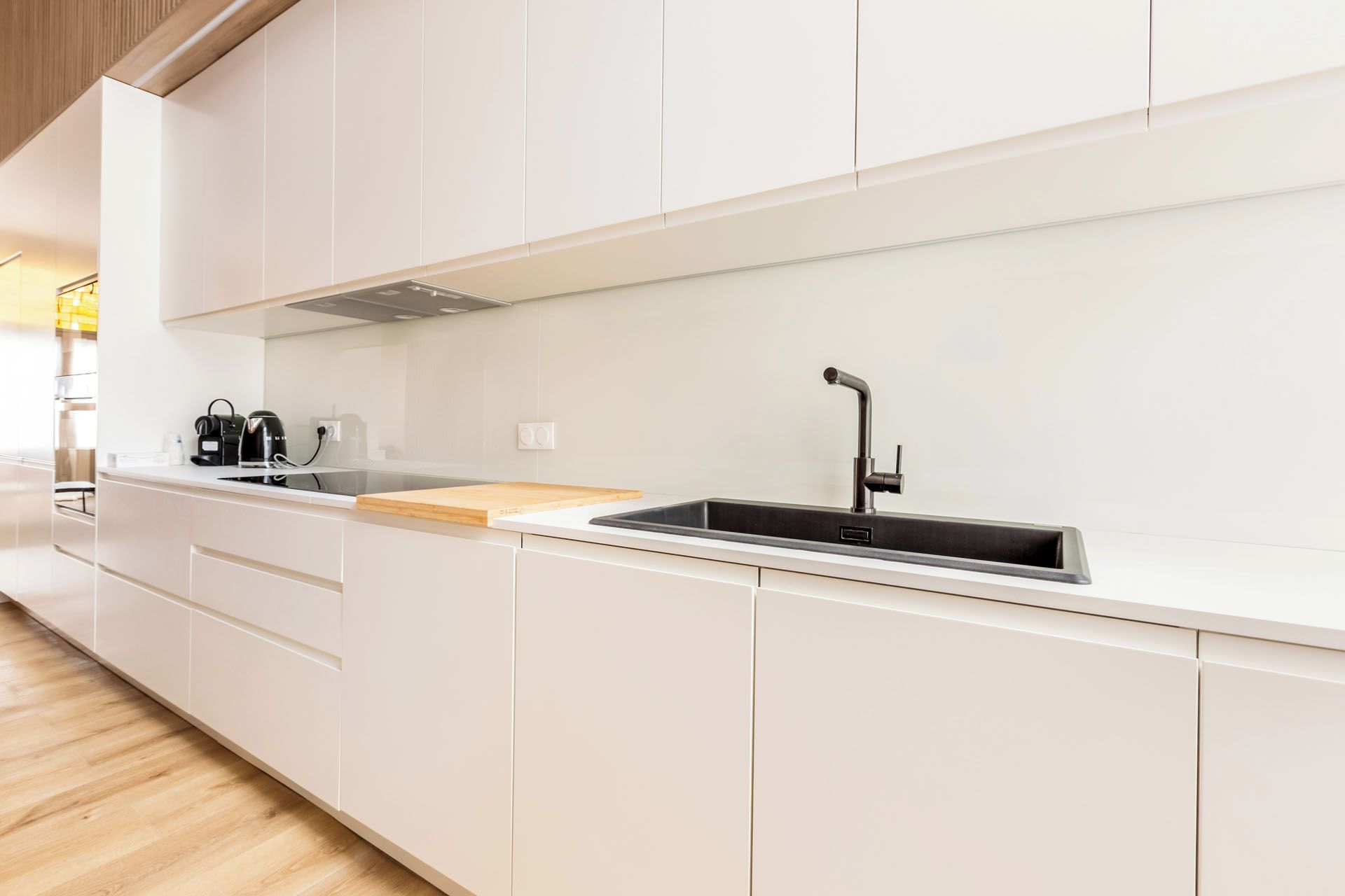 Una cocina moderna con armarios blancos, un lavamanos de acero inoxidable y una encimera de madera.