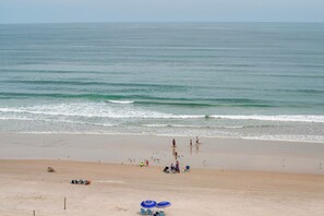 Ein Strand mit freiem Blick auf den Ozean, einem sandigen Ufer und einigen Personen sowie Sonnenschirmen.