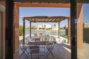 Ein Sitzbereich im Freien mit einer Pergola, einem Pool und Blick auf eine Wohngegend.