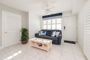 A living room with a dark leather sofa, a wooden coffee table, and a potted plant. - Unit 402 at Towers 10 - Perfect Location with Great Oceanfront Views (Daytona Beach Shores)