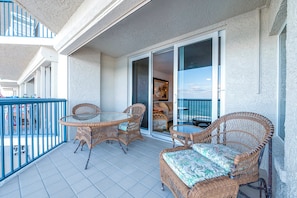 A balcony with wicker furniture, a glass table, and a view of the sea. - #802 Towers 10 Oceanfront 2/2 Condo. (Daytona Beach Shores)