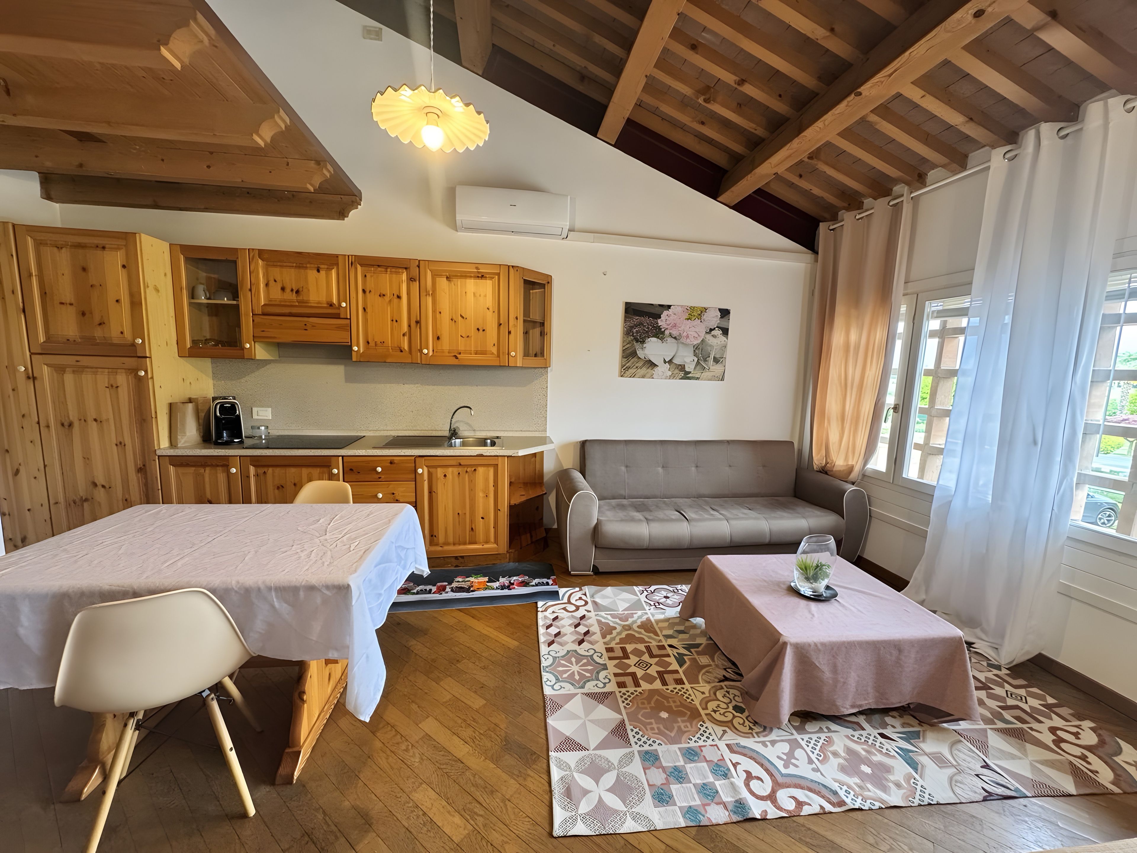 Une pièce chaleureuse avec une table à manger, un canapé, une petite table avec un verre et un tapis à motifs.