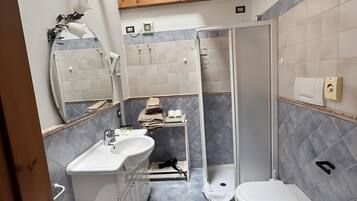 Ein Badezimmer mit Dusche, Toilette, Bidet und Waschbecken.