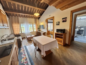 A room with a bed, a desk, a television, and a bathroom visible through an open door. - Apartment 'Nonna Giuseppina - Bilocale' with Shared Pool, Wi-Fi and Air Conditioning (Romano d'Ezzelino)