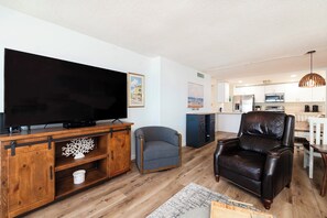 Ein Wohnzimmer mit Flachbildfernseher, Ledersessel, grauem Sessel und einer Holzunterhaltungsecke.