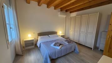 Ein Schlafzimmer mit einem Bett, Nachttischen, einem Kleiderschrank und Holzbalken an der Decke.