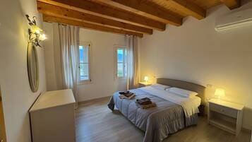 A bedroom with a bed, bedside tables, a mirror, and windows.