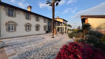 A building with a tiled patio, a palm tree, and red foliage.