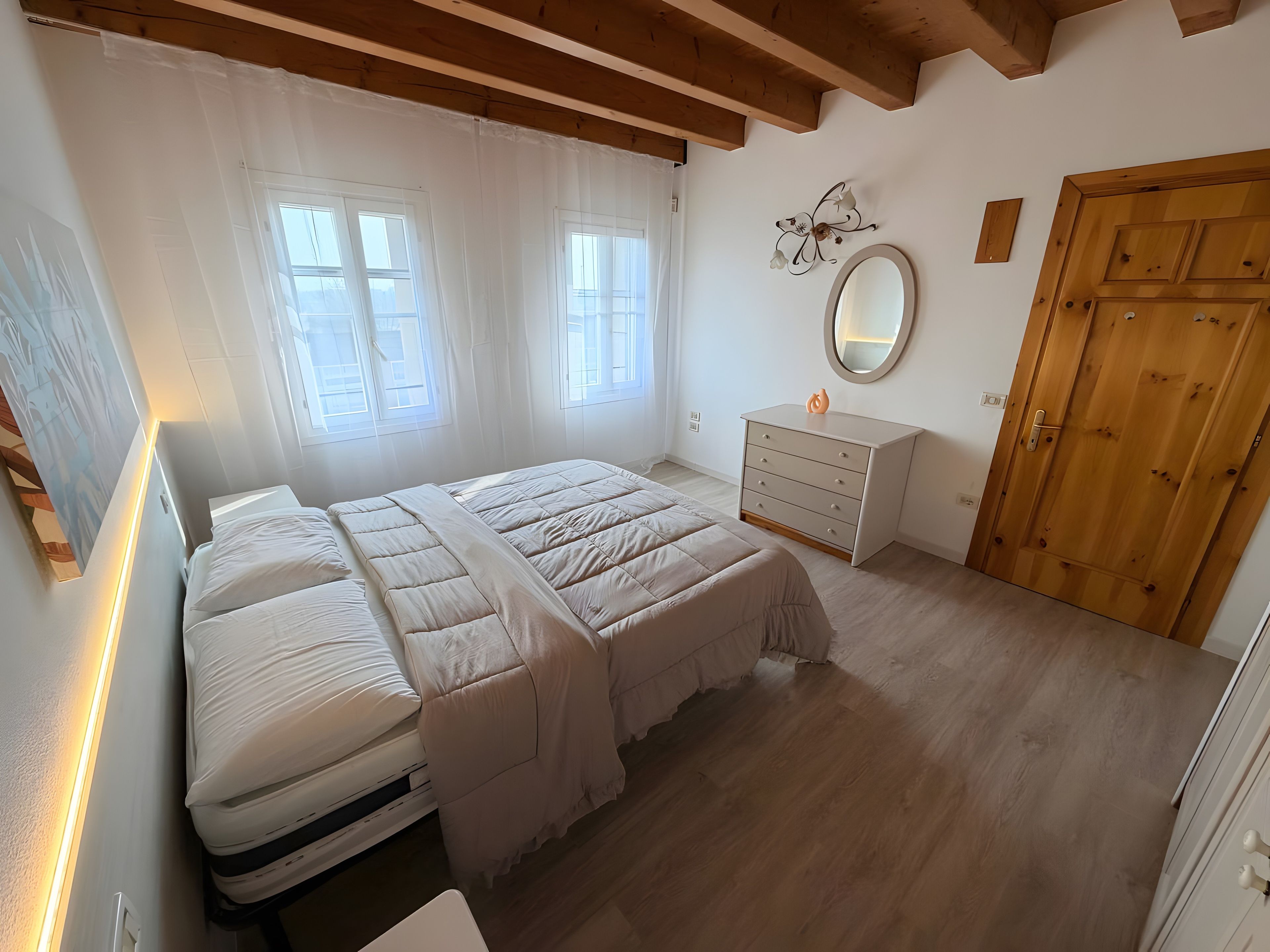 A bedroom with a bed, a dresser, a mirror, and a door.