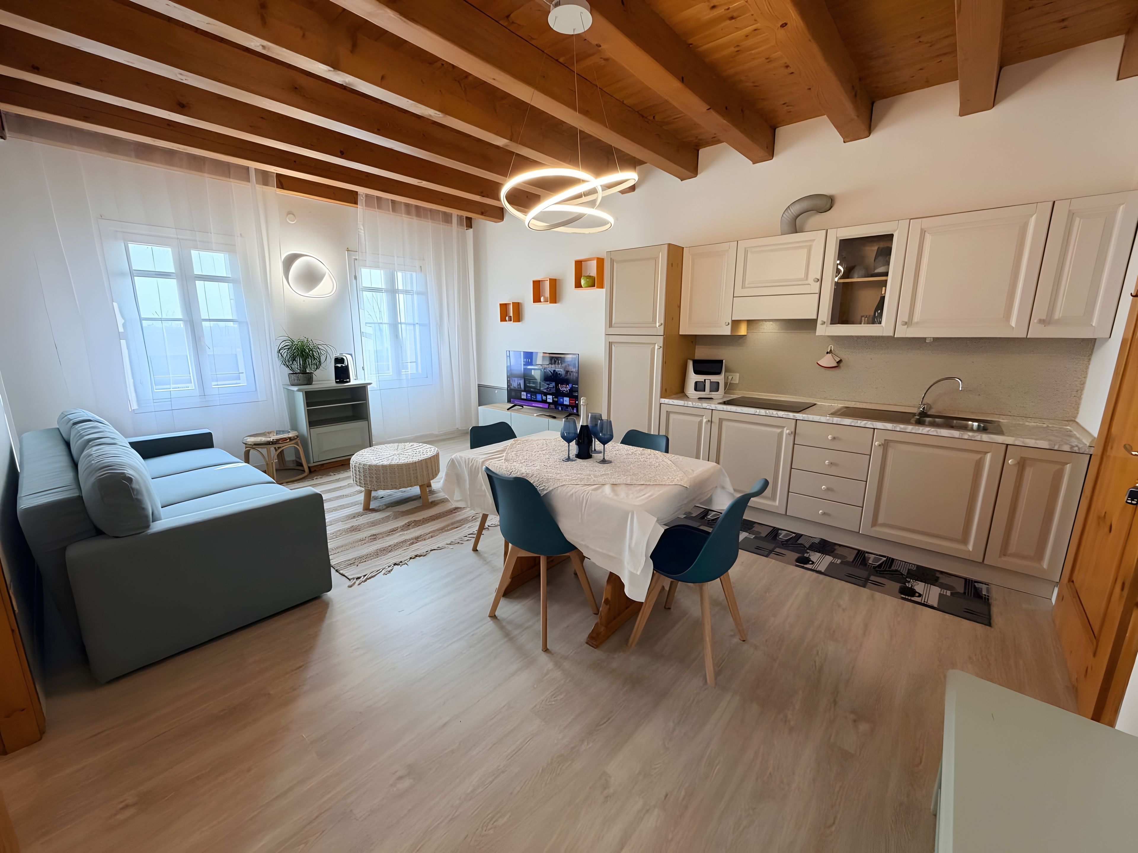 Un salon moderne comprenant un canapé, une table à manger avec des chaises, un coin cuisine avec des placards et un téléviseur.