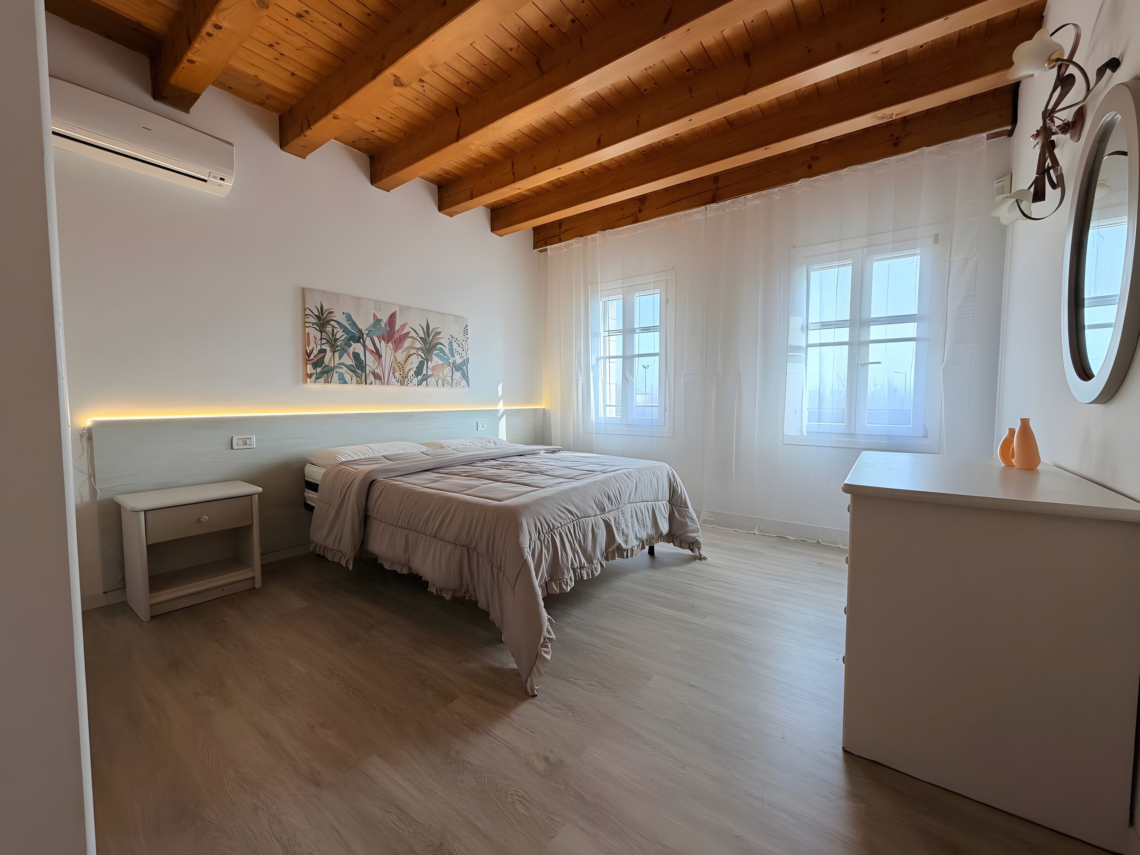A bedroom with a bed, bedside table, dresser, and a ceiling fan.