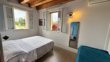 Une chambre à coucher avec un lit, un banc, un miroir et des fenêtres.