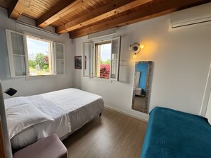 Une chambre à coucher avec un lit, un banc, un miroir et des fenêtres.