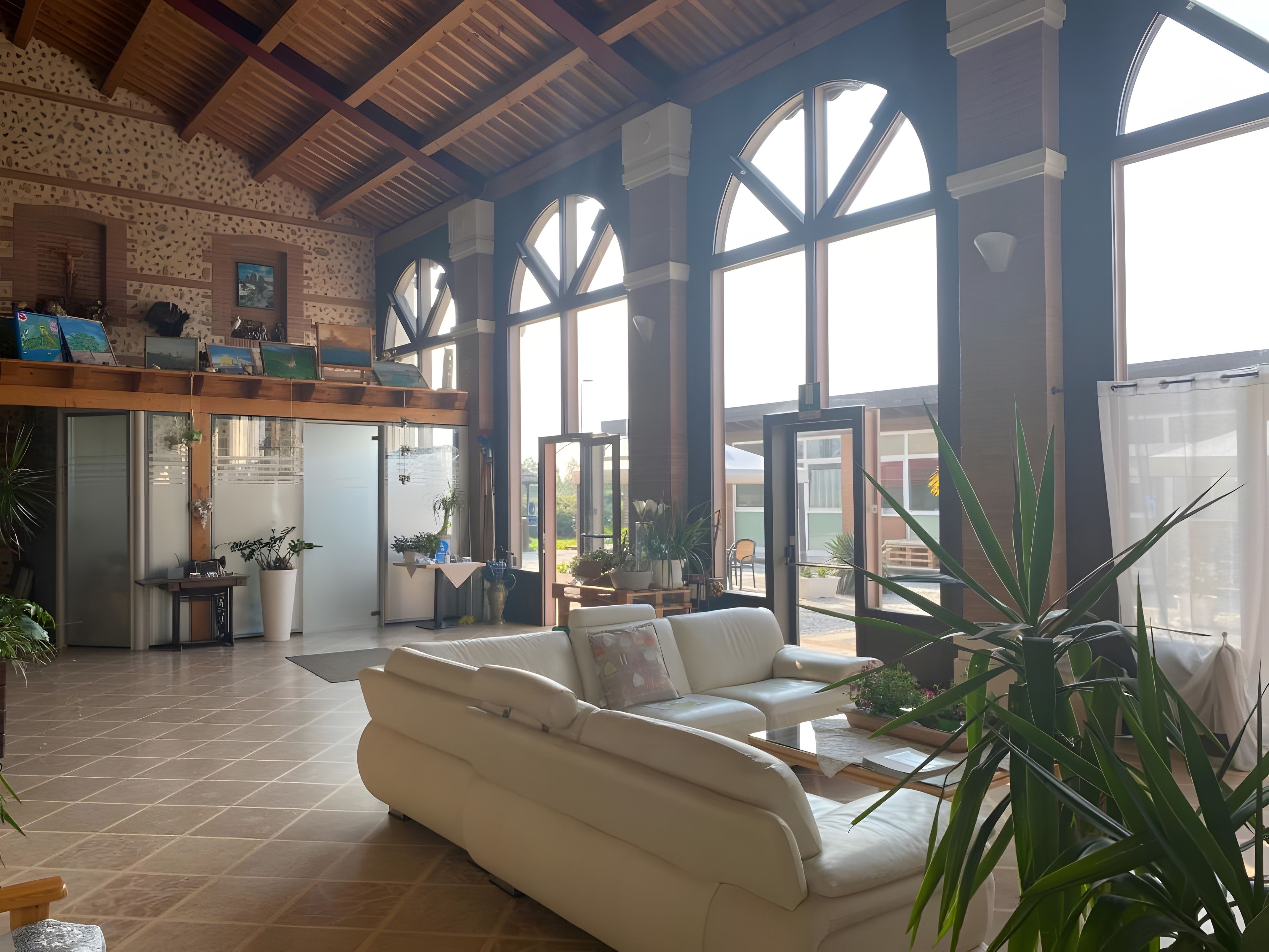 Ein geräumiges Wohnzimmer mit einem weißen Sofa, großen Fenstern und einer Küche im Hintergrund.