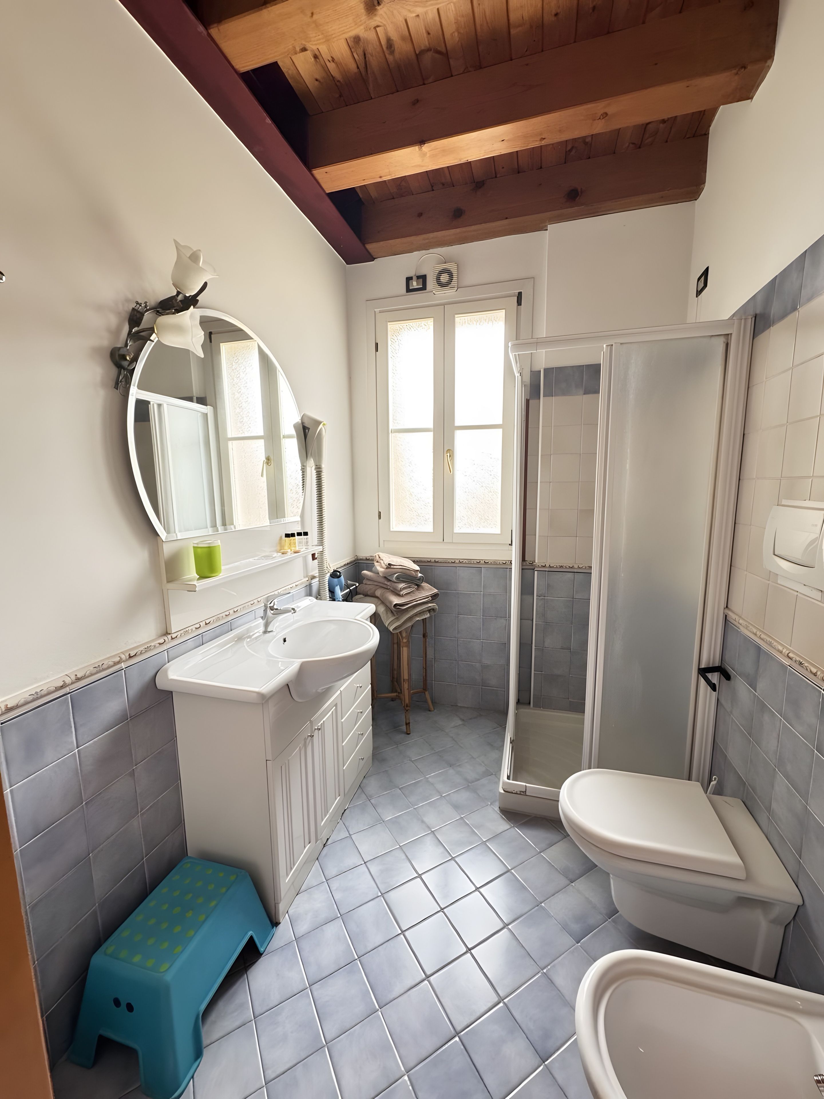 Een badkamer met een douche, toilet, wastafel en een opstapje.