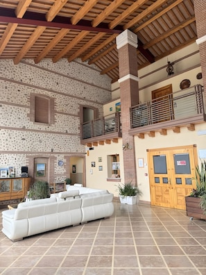 Eine großzügige Lobby mit hoher Decke, einem großen weißen Sofa und einer Holztür mit einem Schild.