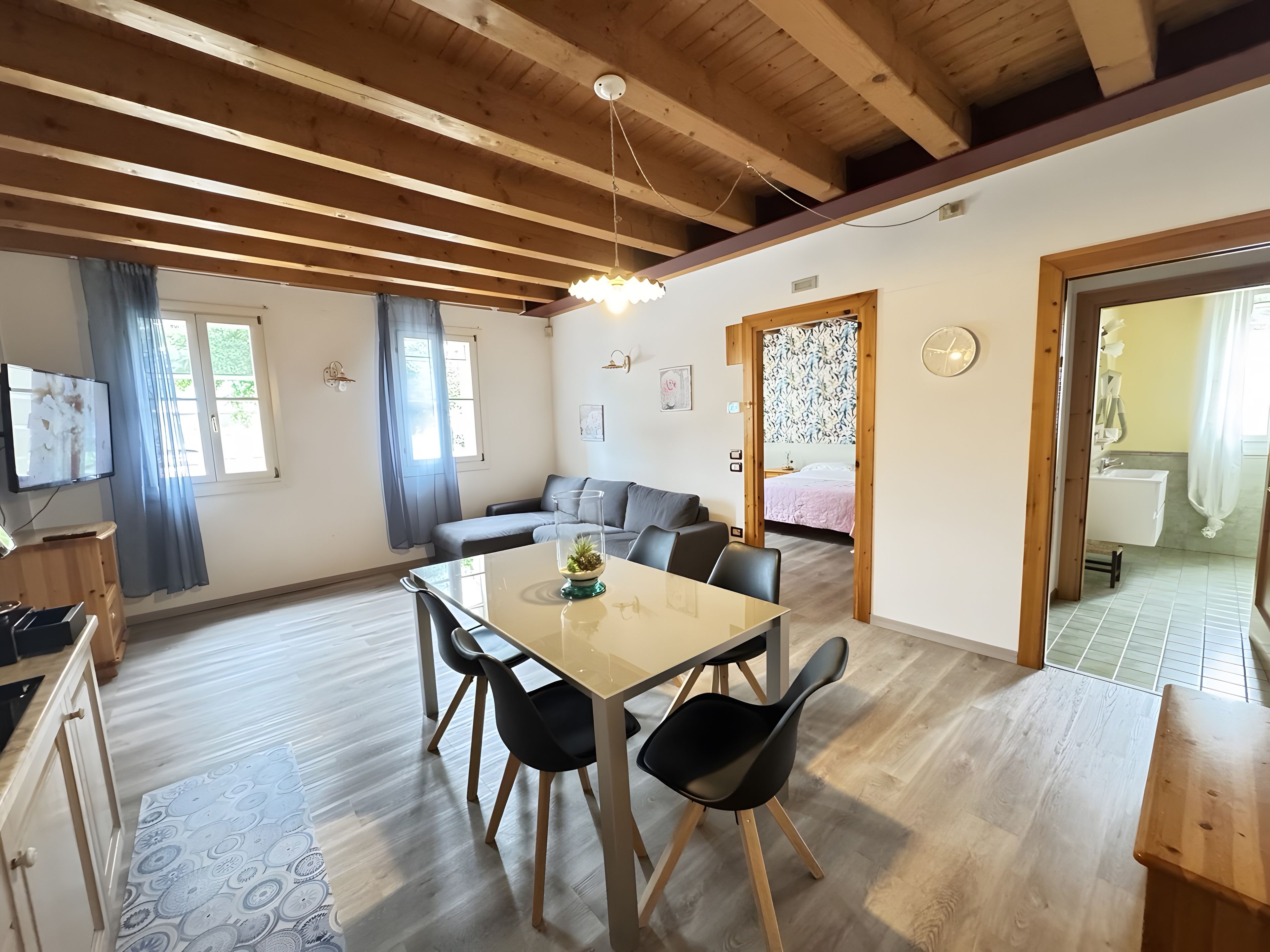 Ein zeitgemäßer Wohnraum mit Essbereich, einer Couch und einem durch eine geöffnete Tür einsehbaren Badezimmer.