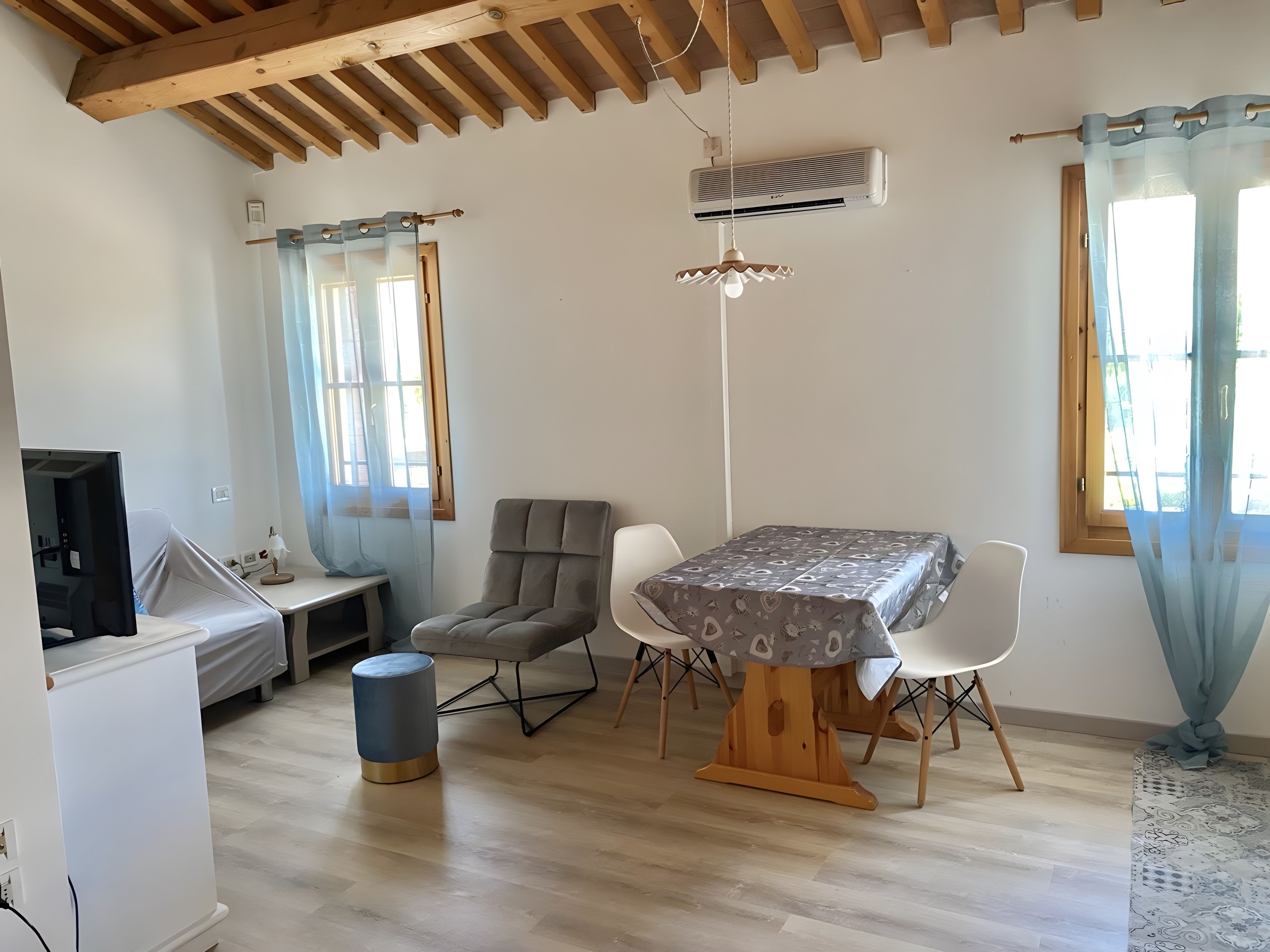 Una habitación con una mesa de comedor, sillas, un televisor y un ventilador de techo.