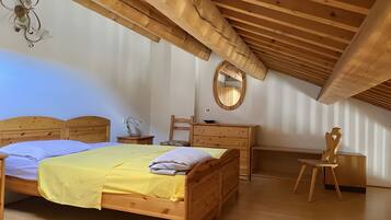 Une chambre à coucher avec un lit en bois, une commode, une chaise, un bureau et un miroir.