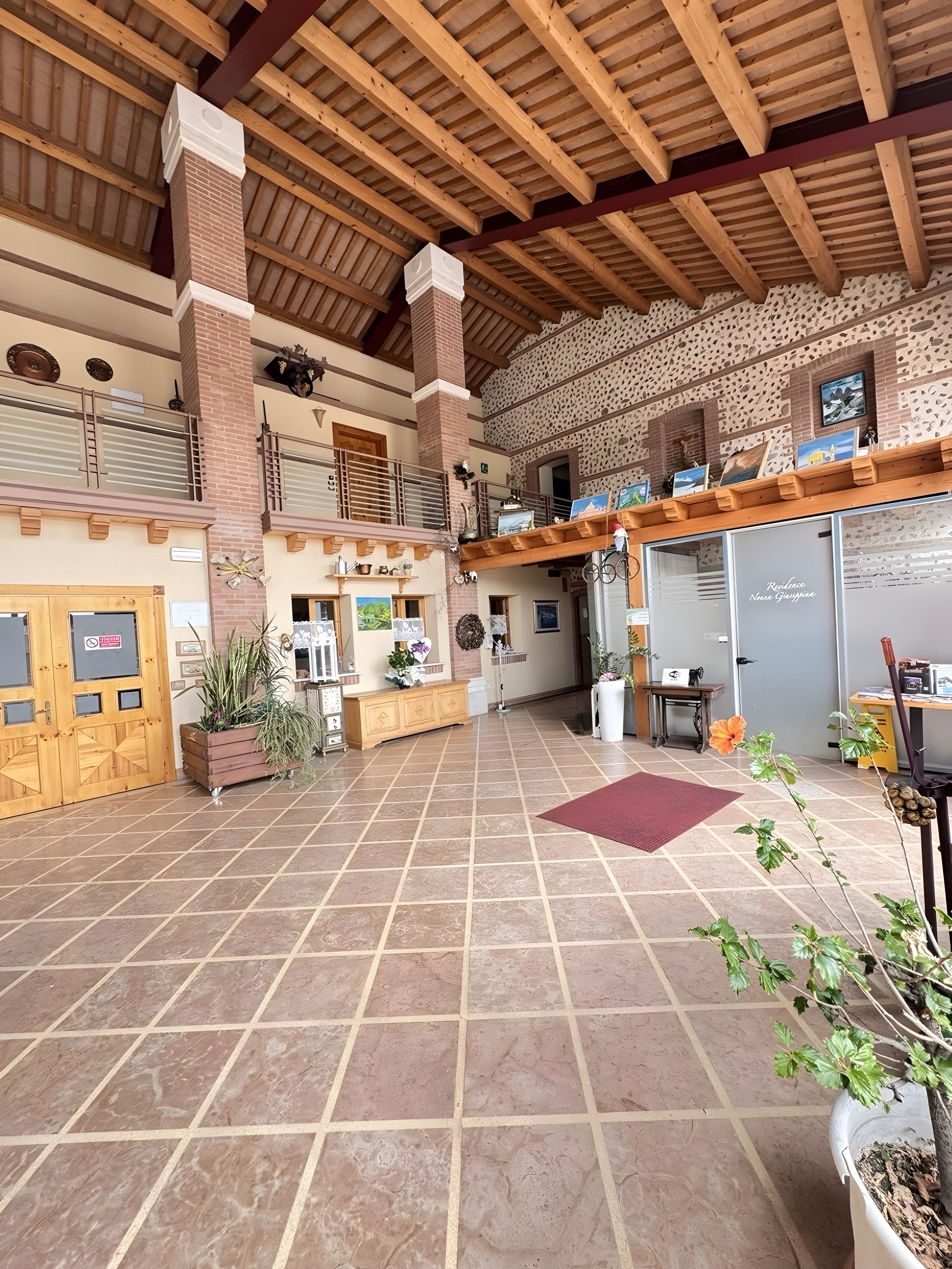 A spacious indoor area with a high ceiling, tiled floor, and a brick wall with a decorative pattern.