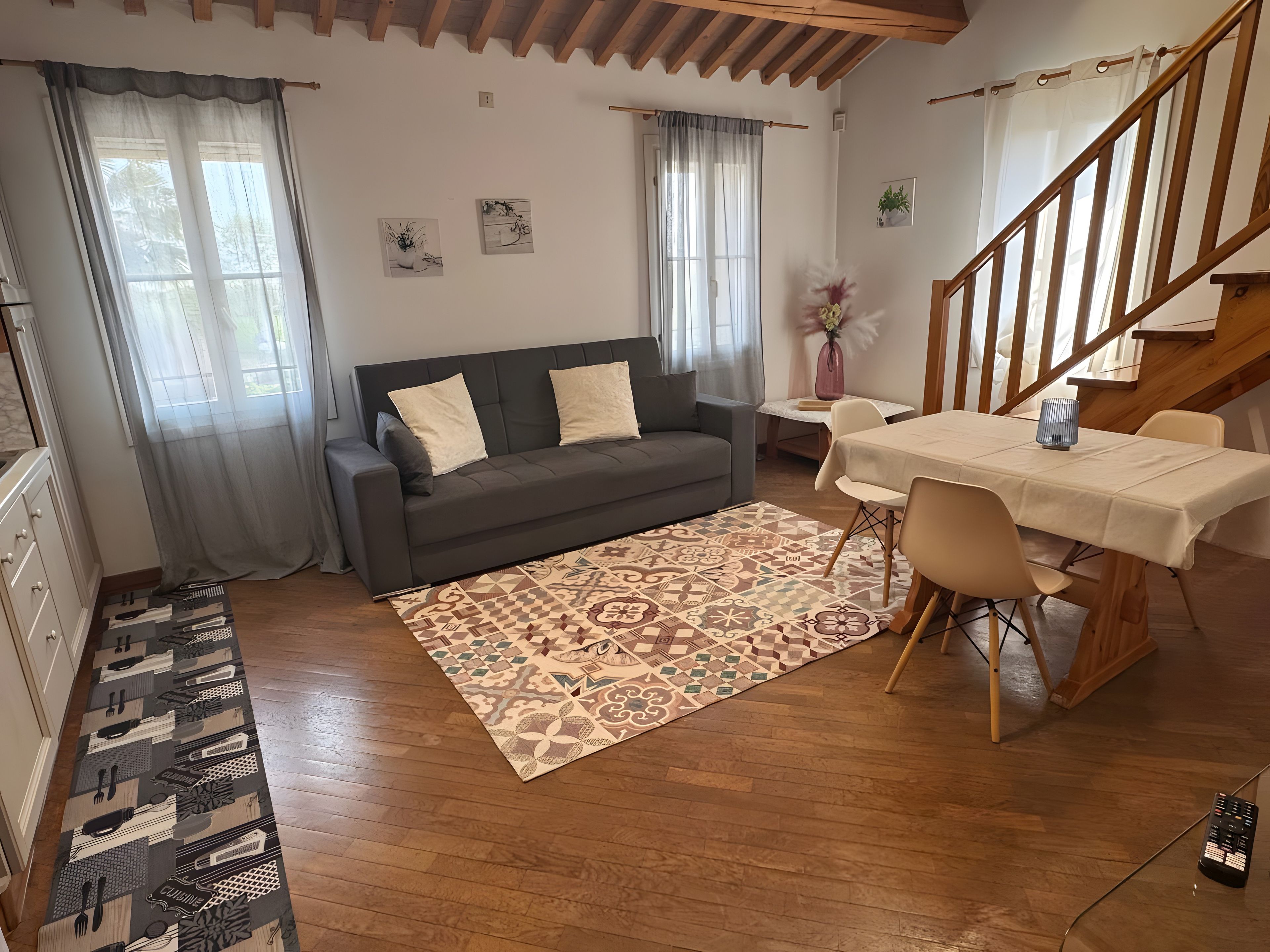 Ein modernes Wohnzimmer mit einer Couch, einem Esstisch, Stühlen, Holzböden und einer Treppe.