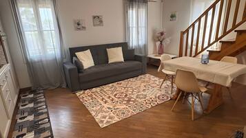 Ein modernes Wohnzimmer mit einer Couch, einem Esstisch, Stühlen, Holzböden und einer Treppe.