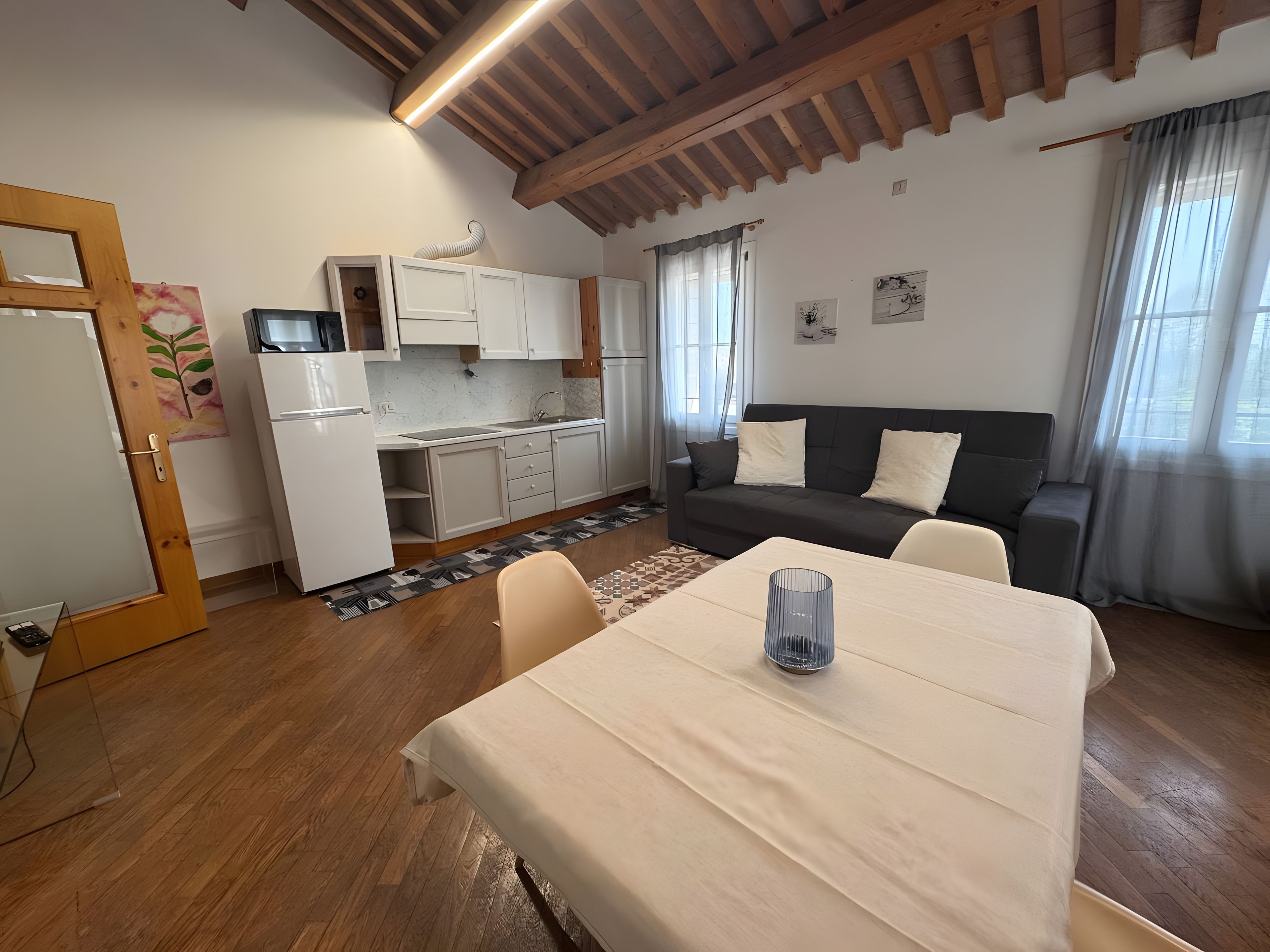 Un espacio habitable compacto con kitchenette, un sofá, una mesa de comedor y techo de madera.