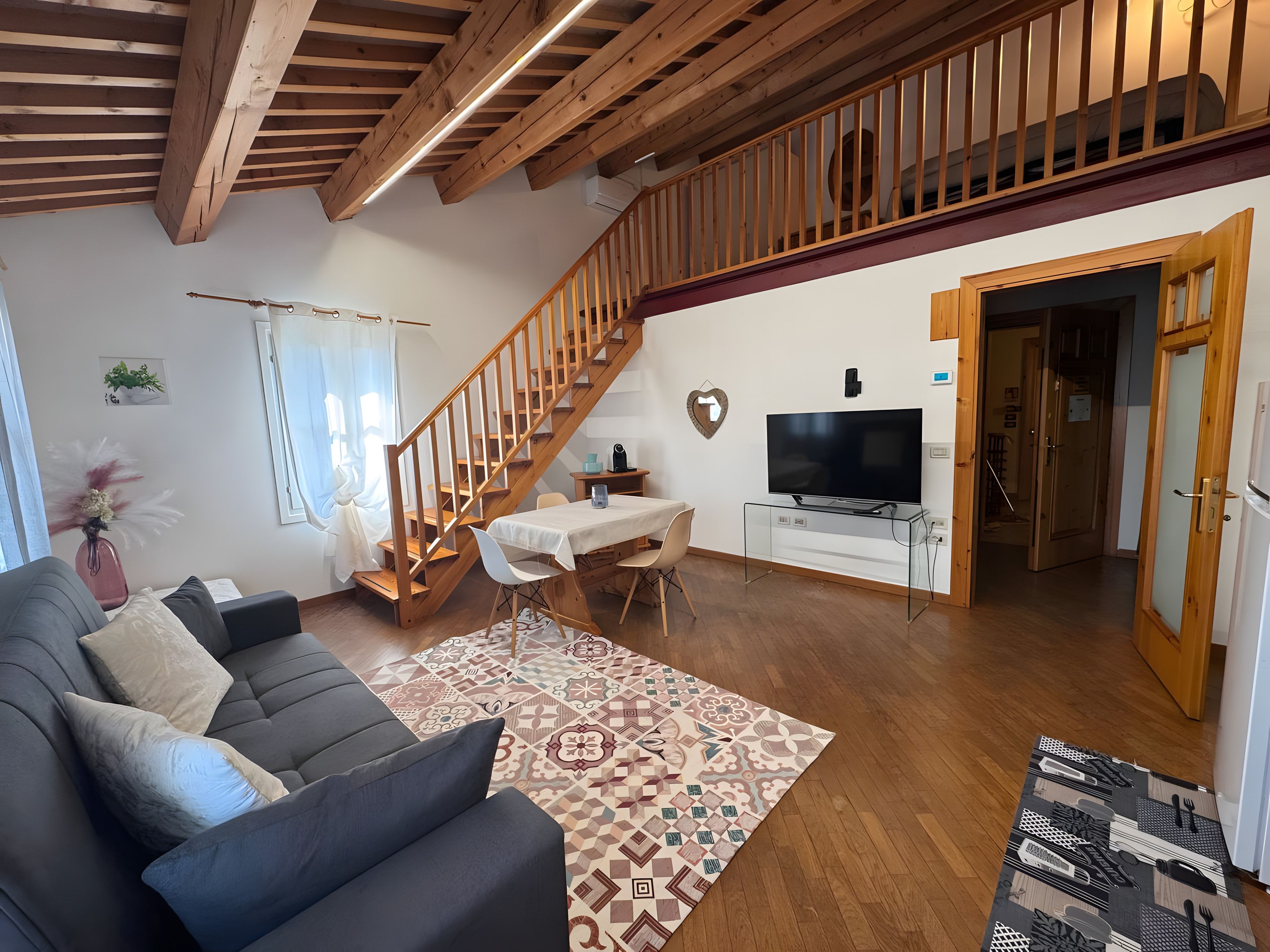 Un salon moderne avec un canapé, une table à manger, un téléviseur et un escalier.